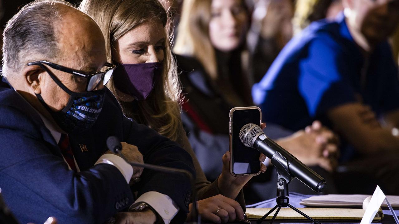 Rudy Giuliani and Jenna Ellis listen as Mr Trump speaks through the latter’s phone. Picture: Samuel Corum/Getty Images/AFP