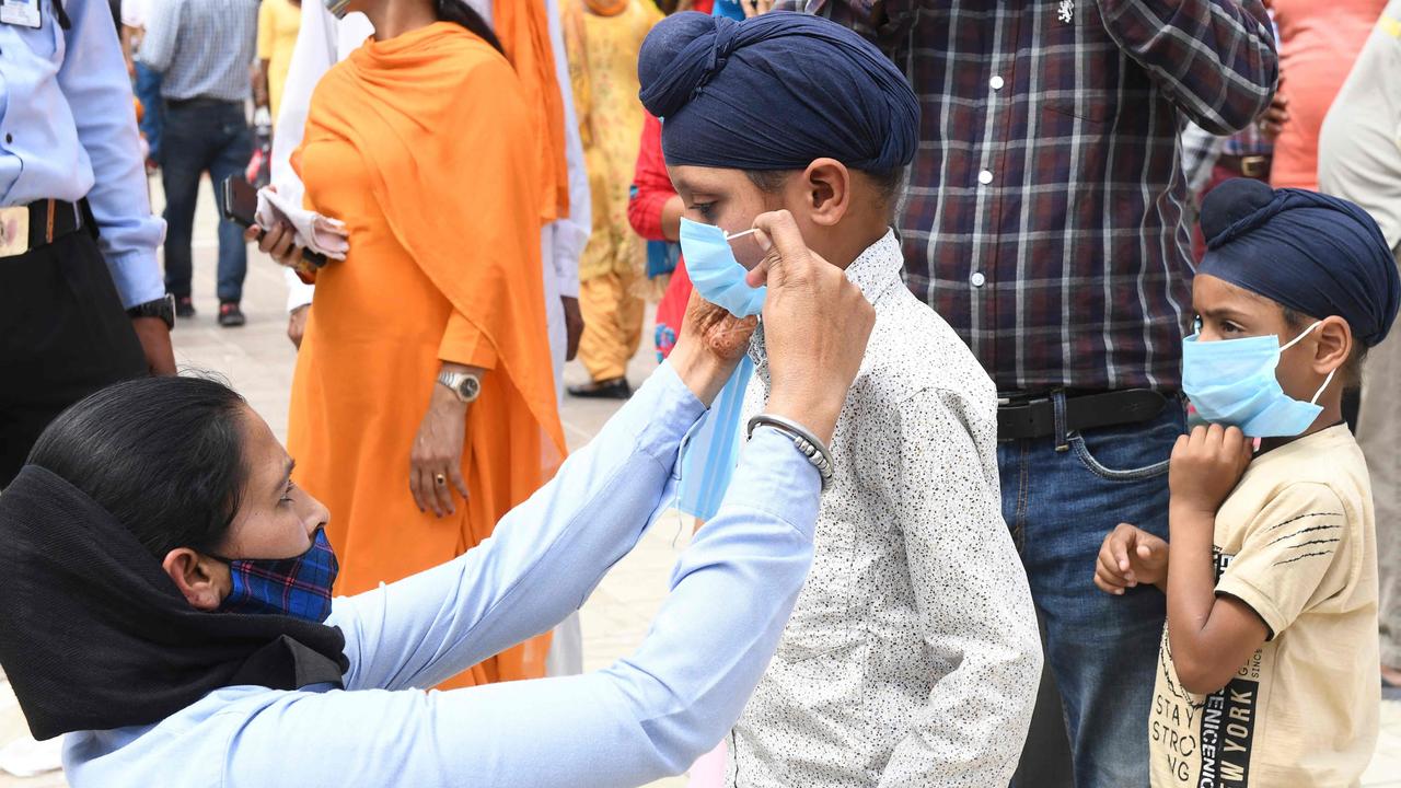 A guard attaches a mask to boy in Amritsar in Punjab last weekend. Picture: Narinder Nanu/AFP