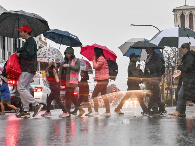 ADELAIDE, AUSTRALIA - NewsWire Photos MAY 30, 2024: Pedestrians cross in Goodwood Rd at Goodwood in the rain. Picture: NCA NewsWire / Brenton Edwards