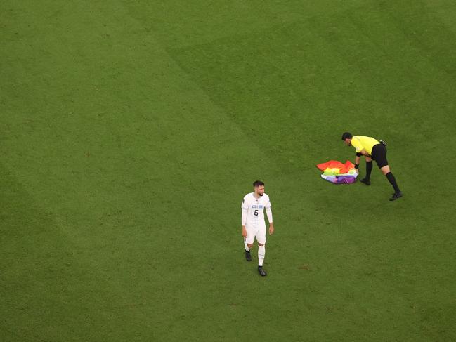 Referee Alireza Faghani picks up a rainbow flag on the pitch. Picture: Ryan Pierse/Getty Images