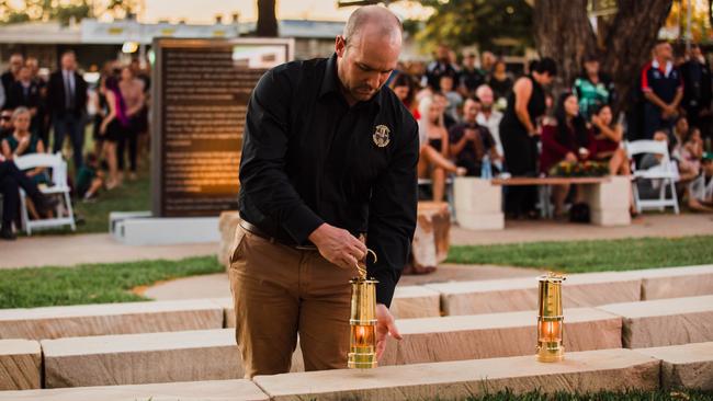 Aaron Smith places a lantern on behalf of family members at last year’s Moranbah Miners' Memorial ceremony.