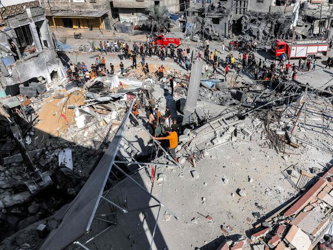 People stand by as civil defence workers search for victims and survivors in the rubble of a building that was hit by Israeli bombardment in Rafah in the southern Gaza Strip. Picture: AFP