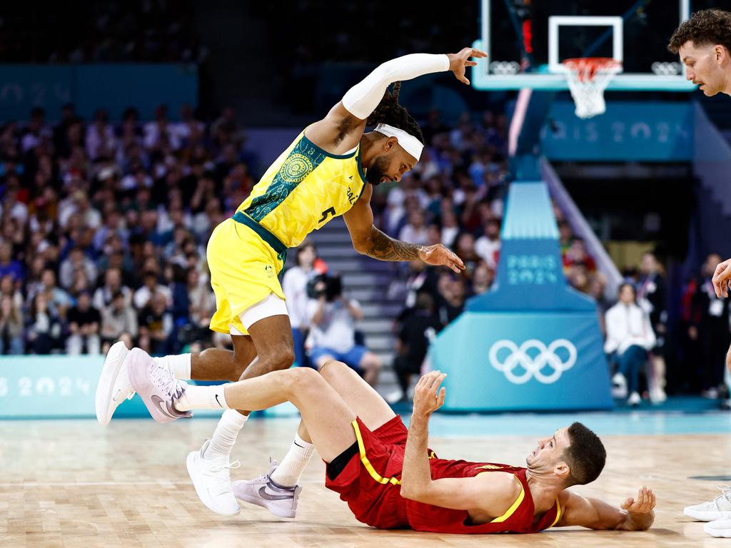 Patty Mills stumbles over Spain's Xabi Lopez-Arostegui during their Games campaign-opening win. Picture: AFP