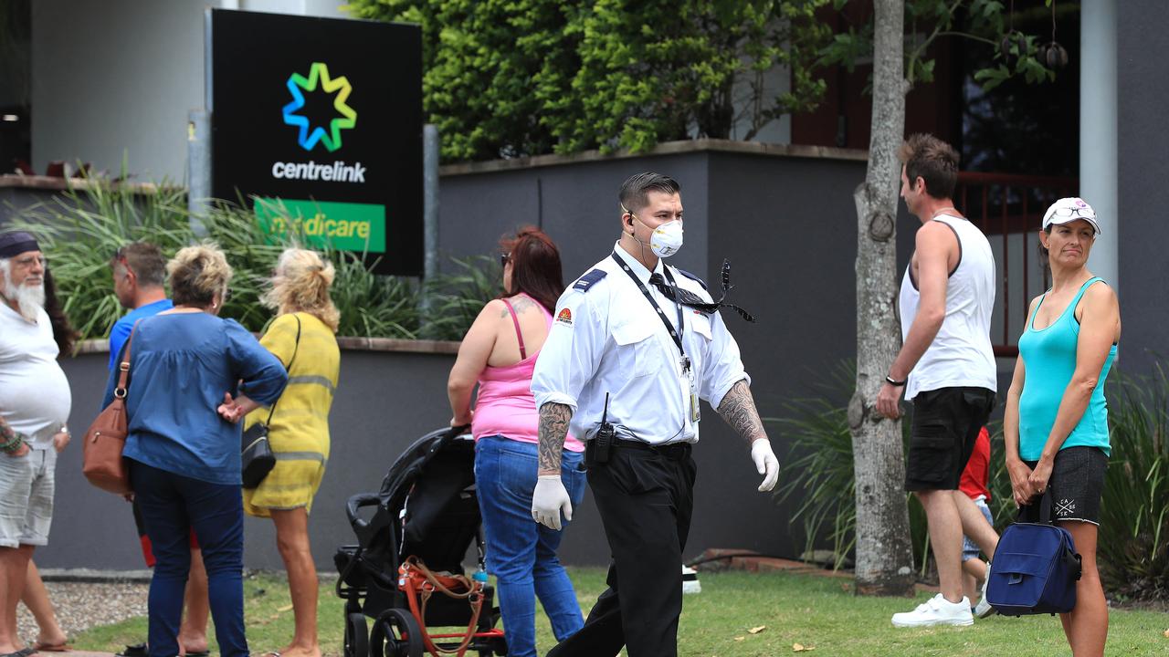 Officials from Centrelink speak to the lines of people waiting at Southport Centrelink. Picture: Adam Head.