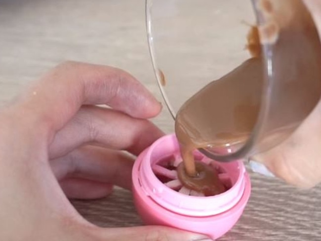 Poor the lipbalm mixture in to the grated side of the REVO container. Picture: Youtube/Cute Life Hacks.