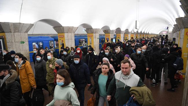 People, some carrying bags and suitcases, walk at a metro station in Kyiv early on February 24.