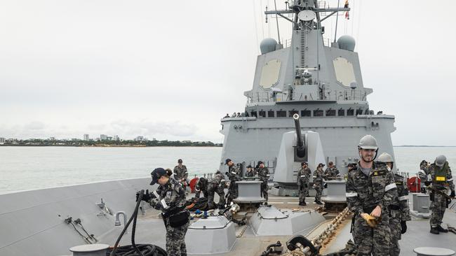 Crew of HMAS Hobart prepare to lower the forward flag staff as the ship departs Darwin on January 17, 2025.