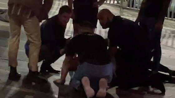 Security and bystanders attend to a man lying prone during the violent altercation.