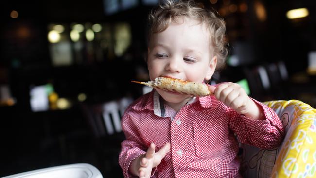 Boy is eating kebab in a high chair at a restaurant