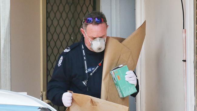 A police officer leaves the family home on Wednesday with what appear to be evidence bags. Picture: Jackson Flindell