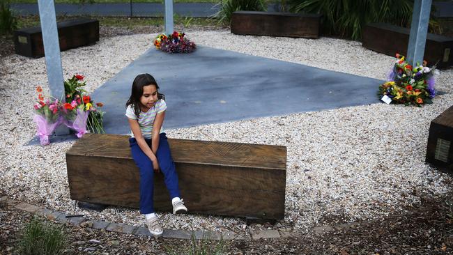 An Aboriginal girl sits at a memorial for the three murdered children. Picture: John Feder