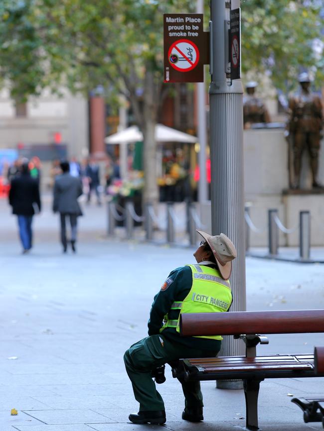 A ranger looks at a no smoking sign in Martin Place, Sydney, which is currently a no smoking zone. Picture: Dylan Robinson.