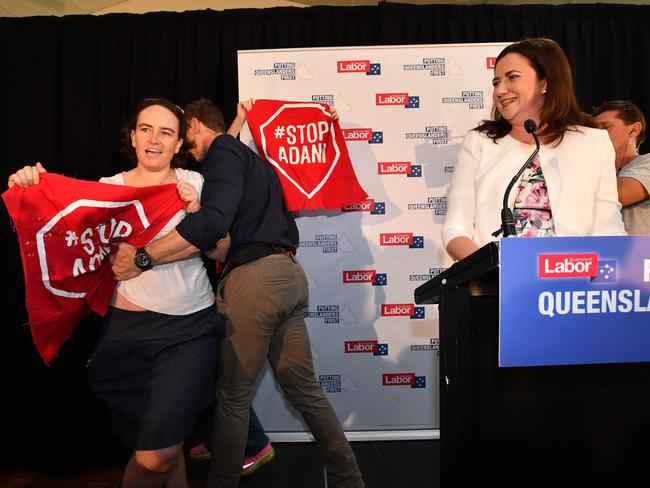 Anti-Adani coal mine protesters invade the stage as Queensland Premier Annastacia Palaszczuk (right) delivers her speech after announcing the date of the Queensland Election at Cementco Bowls Club in Brisbane on Sunday. Picture: Darren England/AAP