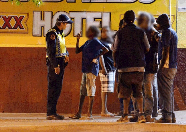 Police talk to locals outside a bottle shop at Peko Park in the centre of the town of Tennant Creek. Picture: Elise Derwin