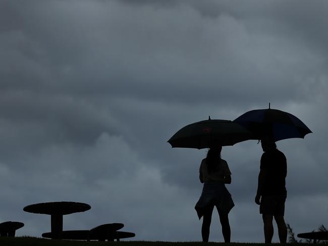 March 17, Queensland, National Park Burleigh Headland - NewsWire Photos March 17, 2021: Catherine and Steven Stevens shelter under their umbrellas and watch the dark rain clouds more in as heavy rain falls over the Gold Coast.Picture: NCA NewsWire / Scott Powick