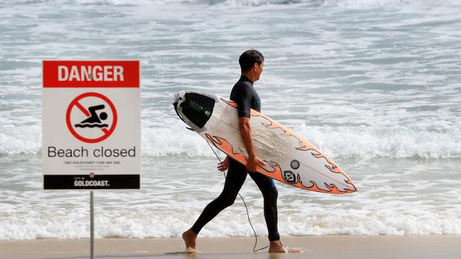 A surfer walks by a beach closed sign at Snapper Rocks after Tuesday’s fatal shark attack at Greenmount point in Coolangatta. Photo: Scott Powick