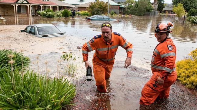 Two SES workers help residents after being flooded apparently due to a water main burst in Willow Drive, Paradise. Picture: Russell Millard