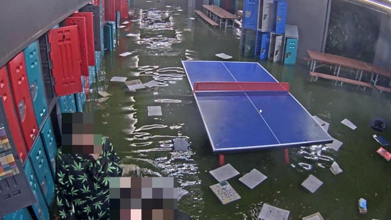 CCTV shared by Emmanuel College, Carrara, appeared to show two teenage girls dumping the contents of student lockers into lapping floodwaters. Picture: Supplied