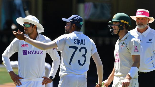 India's Mohammed Siraj, centre, gestures next to Australia's captain Tim Paine (2R) as the game was halted. Picture: AFP