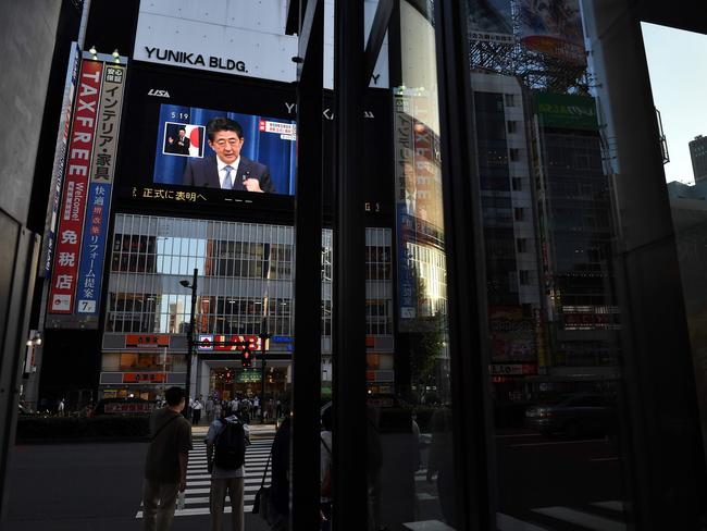 Japanese Prime Minister Shinzo Abe was seen on a large screen giving during a live press conference in Tokyo where he made his announcement. Photo: Philip FONG AFP