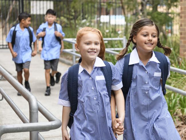 Female primary school students wearing blue gingham dresses with boys in background Picture: Istock