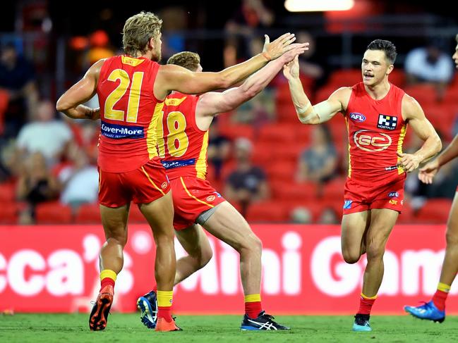 Ben Ainsworth (right) of the Suns celebrates kicking a goal with the mates during the AFL Marsh Community Series pre-season match between the Gold Coast Suns and Geelong Cats at Metricon Stadium on the Gold Coast, Saturday, February 22, 2020. (AAP Image/Darren England)