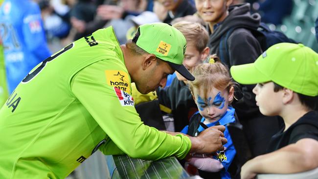 Usman Khawaja signs a Thunder fan’s jersey after the match against the Strikers on Saturday night. Picture: AAP Image/David Mariuz