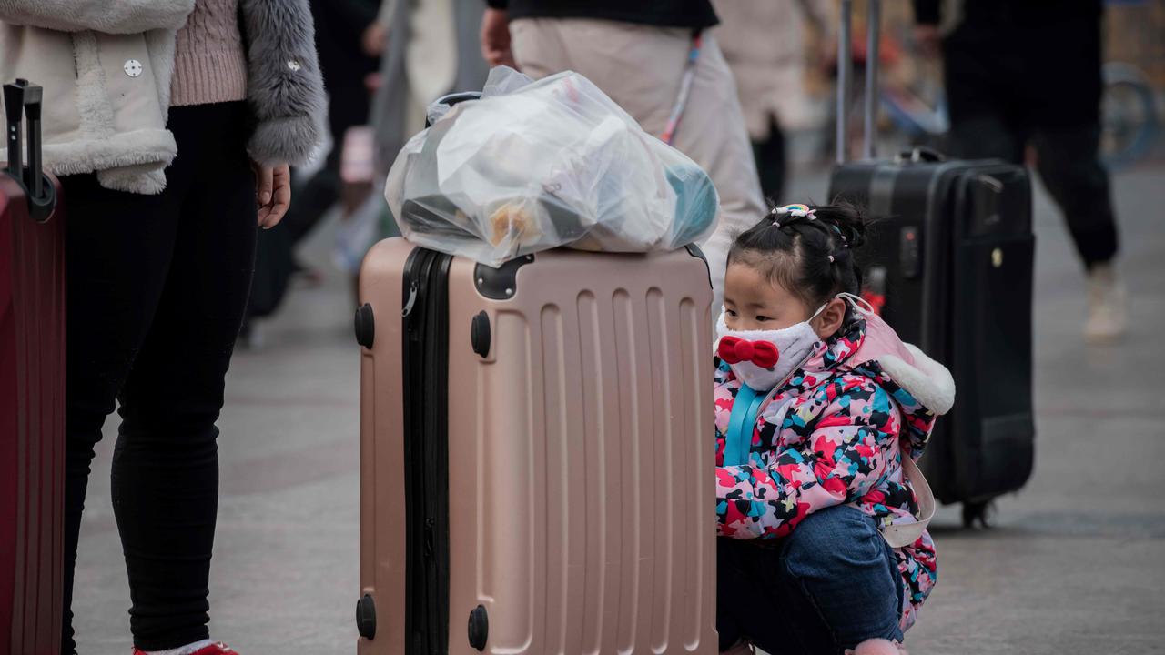 A girl wearing a protective facemask to help stop the spread of a deadly virus which began in Wuhan, is seen at the Beijing railway station. Picture: AFP