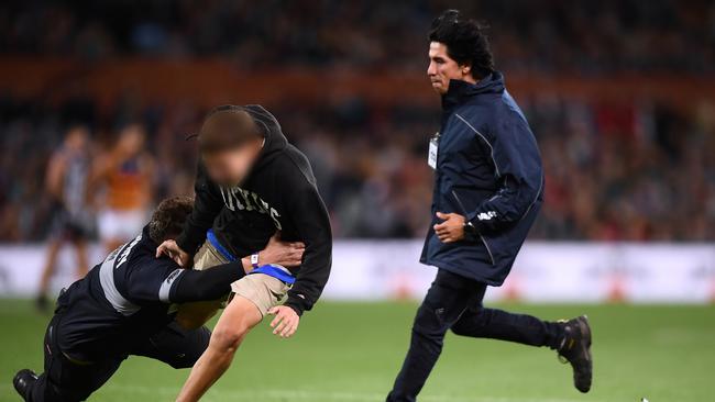 A pitch invader is tackled by security at Adelaide Oval during the round three Showdown between Port Adelaide. Picture: Mark Brake/Getty Images