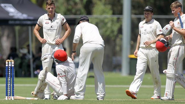 Adelaide batsman James Takos cops a blow to the head off the bowling of Nick Winter for University, which brought him down. Players gather around to check on him. Picture: AAP/Dean Martin