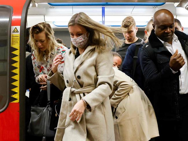 Commuters, some wearing face coverings to help prevent the spread of coronavirus, walk out of a Transport for London (TfL) underground train in London on October 20, 2021. - Healthcare leaders urged the British government to reinstate some coronavirus restrictions to ease pressures on hospitals because of spiralling case numbers. But ministers remain opposed to reintroducing any curbs, arguing the situation is still far better than earlier this year and the country is learning to "live with the virus". (Photo by Tolga Akmen / AFP)