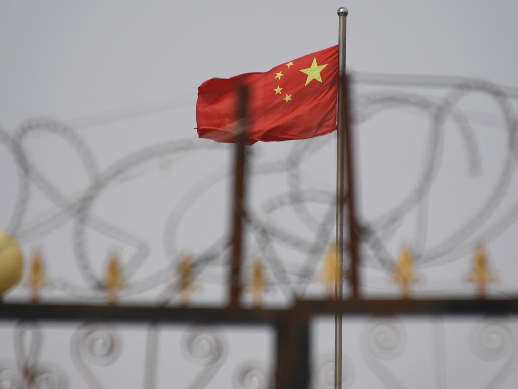 A Chinese flag behind razor wire at a housing compound in Yangisar, south of Kashgar, in China's western Xinjiang region. Picture: Greg Baker/AFP