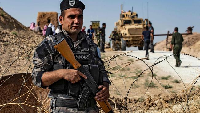 A member of Kurdish security forces stands guard during a demonstration by Syrian Kurds against Turkish threats next to a base for the US-led international coalition on the outskirts of Ras al-Ain town in Syria's Hasakeh province near the Turkish border. Picture: AFP