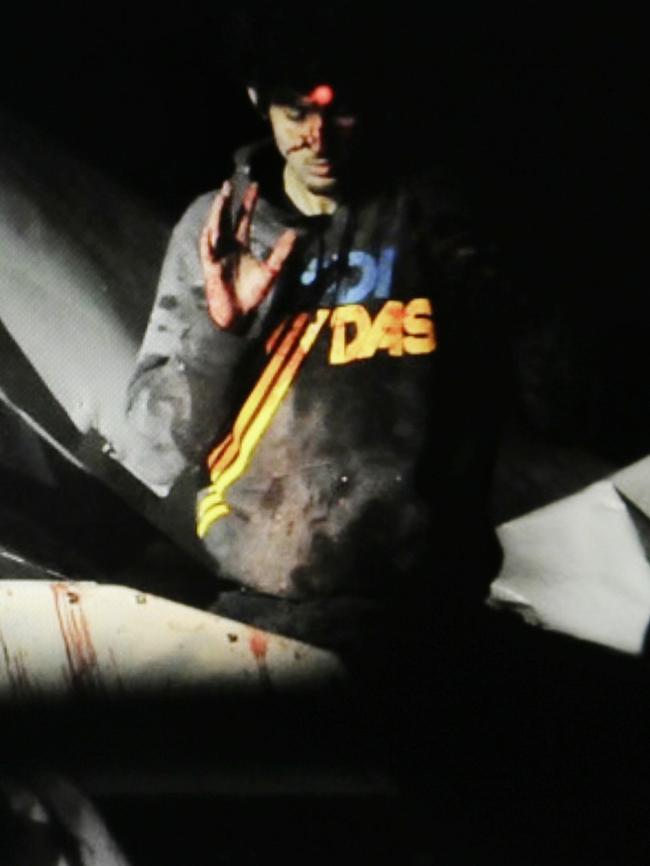 19-year-old Boston Marathon bombing suspect Dzhokhar Tsarnaev, bloody and disheveled with the red dot of a sniper's rifle laser sight on his forehead, raises his hand from inside a boat at the time of his capture by law enforcement authorities in Watertown.