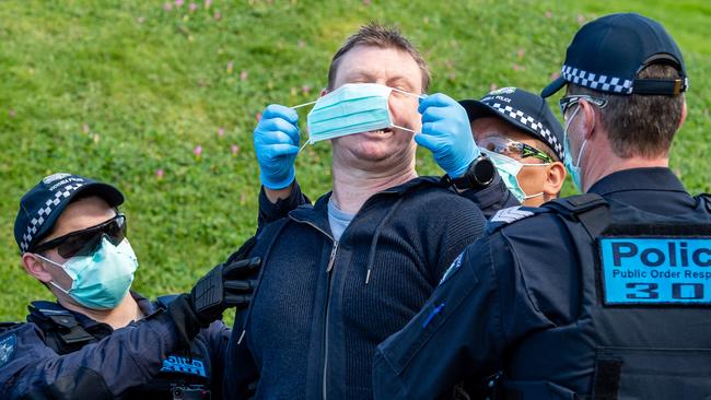 Police attempt to put a mask on a protester at an anti Covid-19 lockdown rally at the Shrine of Remembrance, Melbourne. Picture: Jake Nowakowski