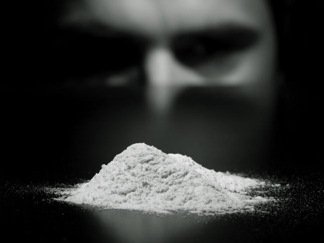 Young man cocaine addicted looking with temptation to white powder. Focus on white powder