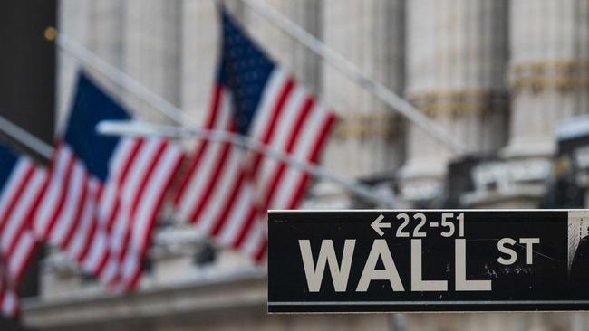 (FILES) In this file photo a Wall St sign hangs at the New York Stock Exchange (NYSE) at Wall Street on March 23, 2021 in New York City. - The Dow surged above 35,000 for the first time on May 10, 2021, extending a run of records as investors pumped funds into industrial companies expected to benefit from the US economic recovery. Near 1515 GMT, the Dow Jones Industrial Average was up 0.8 percent at 35,042.95. The blue-chip index has closed at records the last three sessions. (Photo by Angela Weiss / AFP)