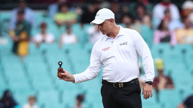 Umpire Donovan Koch takes a light meter reading over the stumps during a delay. Picture: AFP