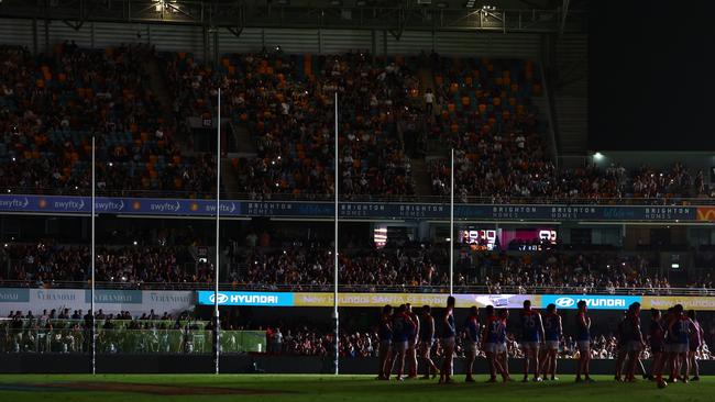 Players wait on field after the power goes out during the Brisbane Lions v Melbourne Demons clash at The Gabba on Friday night. Picture: Chris Hyde/Getty Images