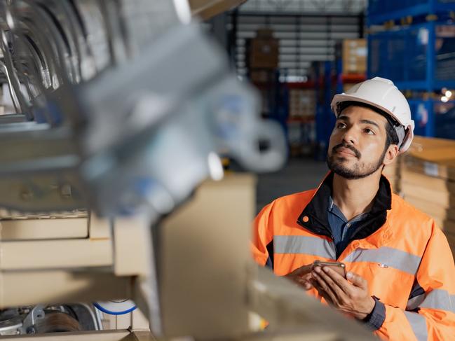 Young man industrial engineer wearing a white helmet while check the welding on the production line in the factory.