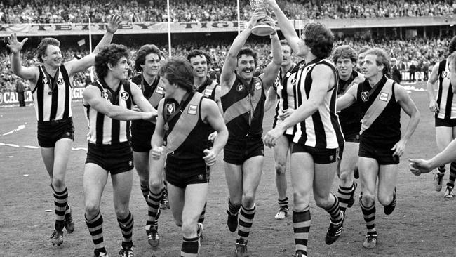 Michael (Mick) Malthouse holds the 1980 premiership cup and celebrates with teammates Michael Roach, Stephen Mount, Geoff Raines, Dale Weightman, Francis Bourke, Robert Wiley and Jim Jess.