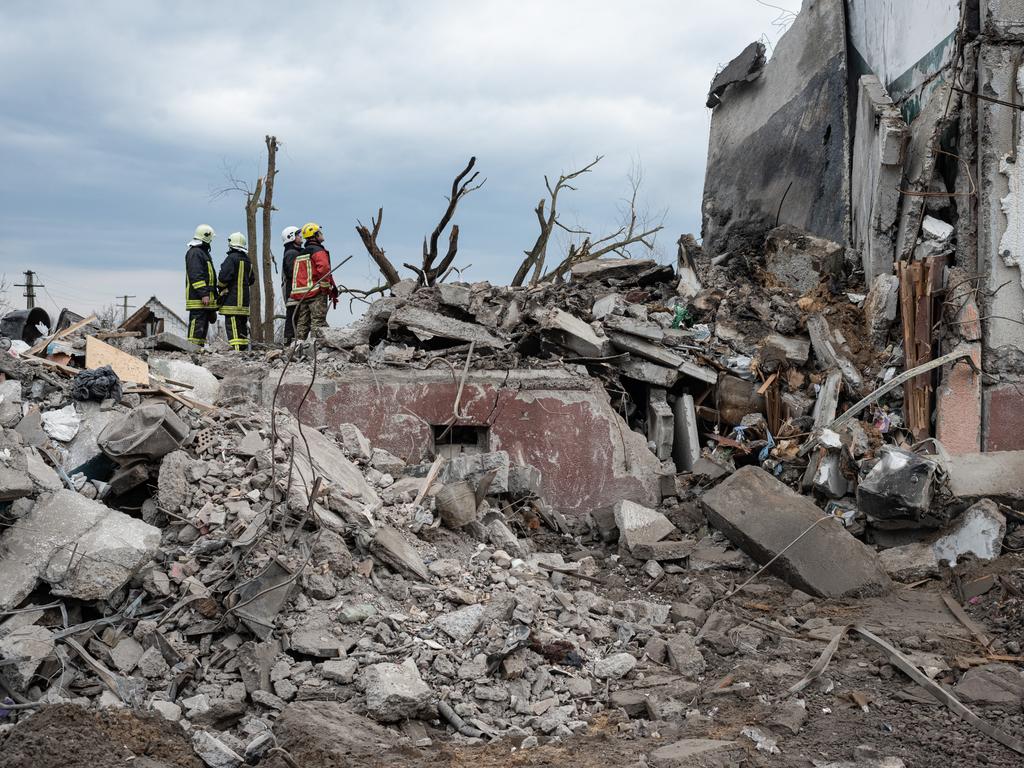 Rescue workers watch their colleague pulling a body out of the rubble after the Russian retreat from towns near Kyiv revealed hundreds of civilian deaths. Picture: Getty Images