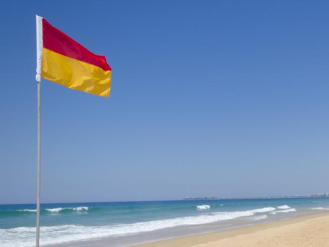 Twin Waters North Shore, Australia - September 22, 2012: Image features Surf life saver red and yellow flags and lifeguard surfboard on beach.