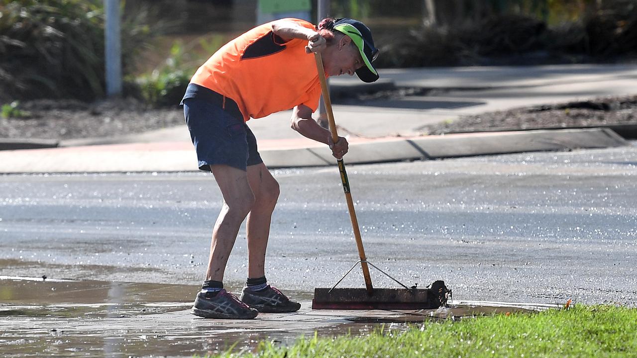 A worker mops mud off a footpath. Picture: AAP Image/Dan Peled