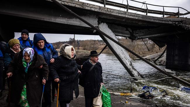 Elderly evacuees are helped to cross a destroyed bridge as they flee the city of Irpin, northwest of Kyiv. Picture: AFP