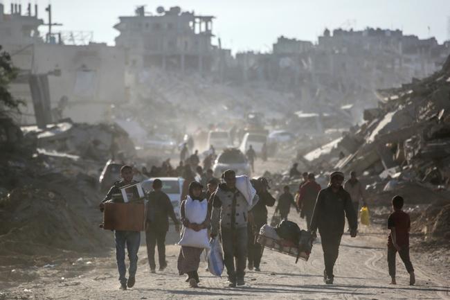 Palestinians carry their belongings as they return to Rafah in southern Gaza, surrounded by destruction