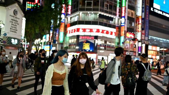 People wearing face masks cross a street in Tokyo’s Shinjuku area. Picture: AFP