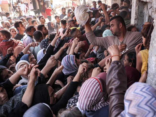 A man prepares to toss a bag of bread as people crowd while queueing for bread outside a bakery in Khan Yunis in the southern Gaza Strip. Picture: AFP