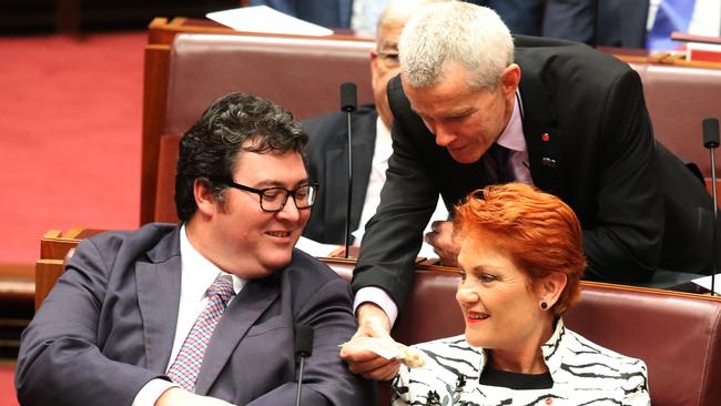 Pauline Hanson and George Christensen are offered a bag of cashews from Malcolm Roberts. Picture: Gary Ramage