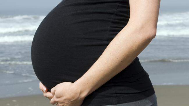 Undated : generic pregnant woman wearing a black top holding / cradling her stomach. Pic. ISTOCK